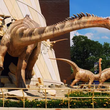 A huge dinosaur model appears to burst through the walls of a building at the children's museum in Indianapolis