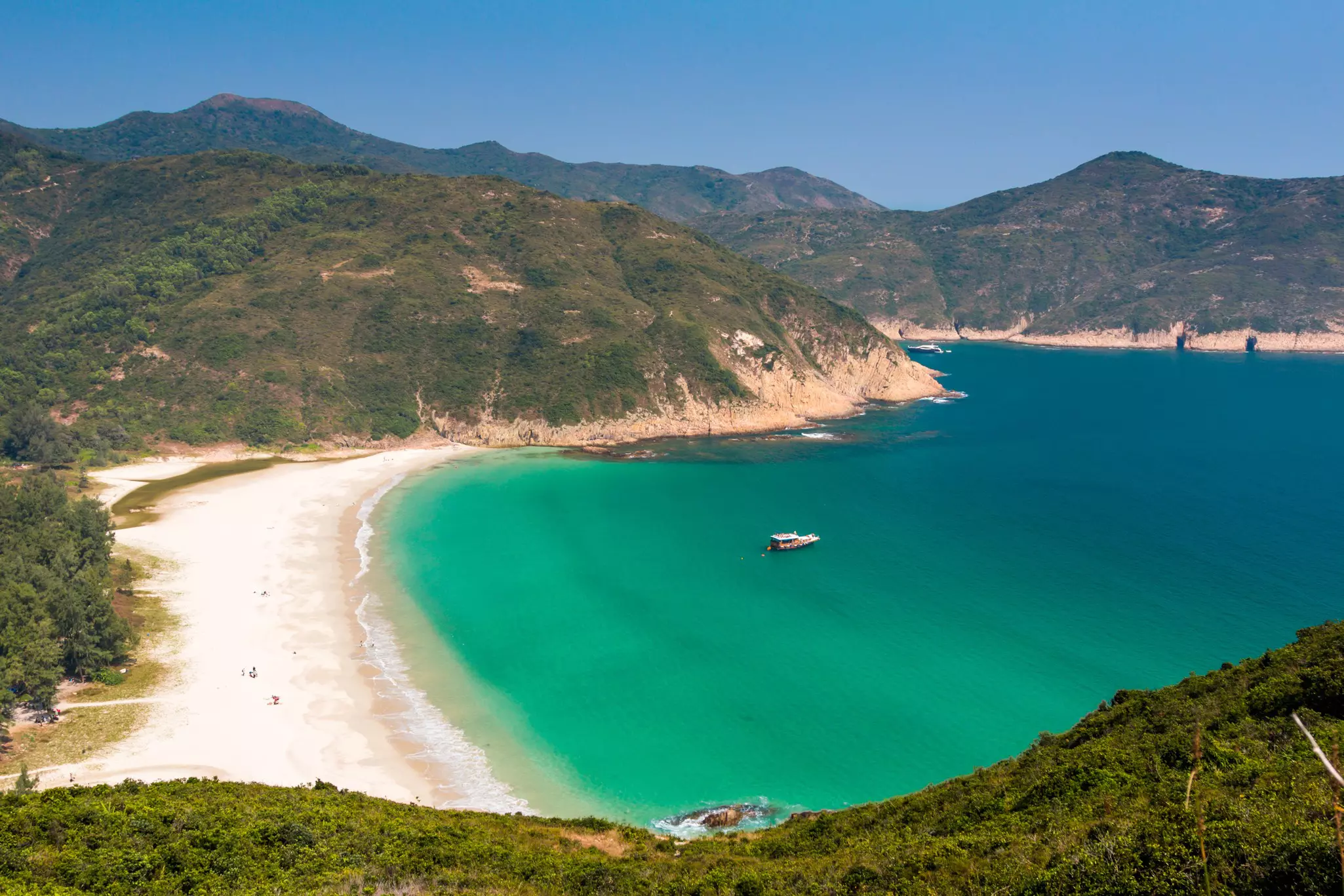 A beach sheltered by large cliffs on either side. 