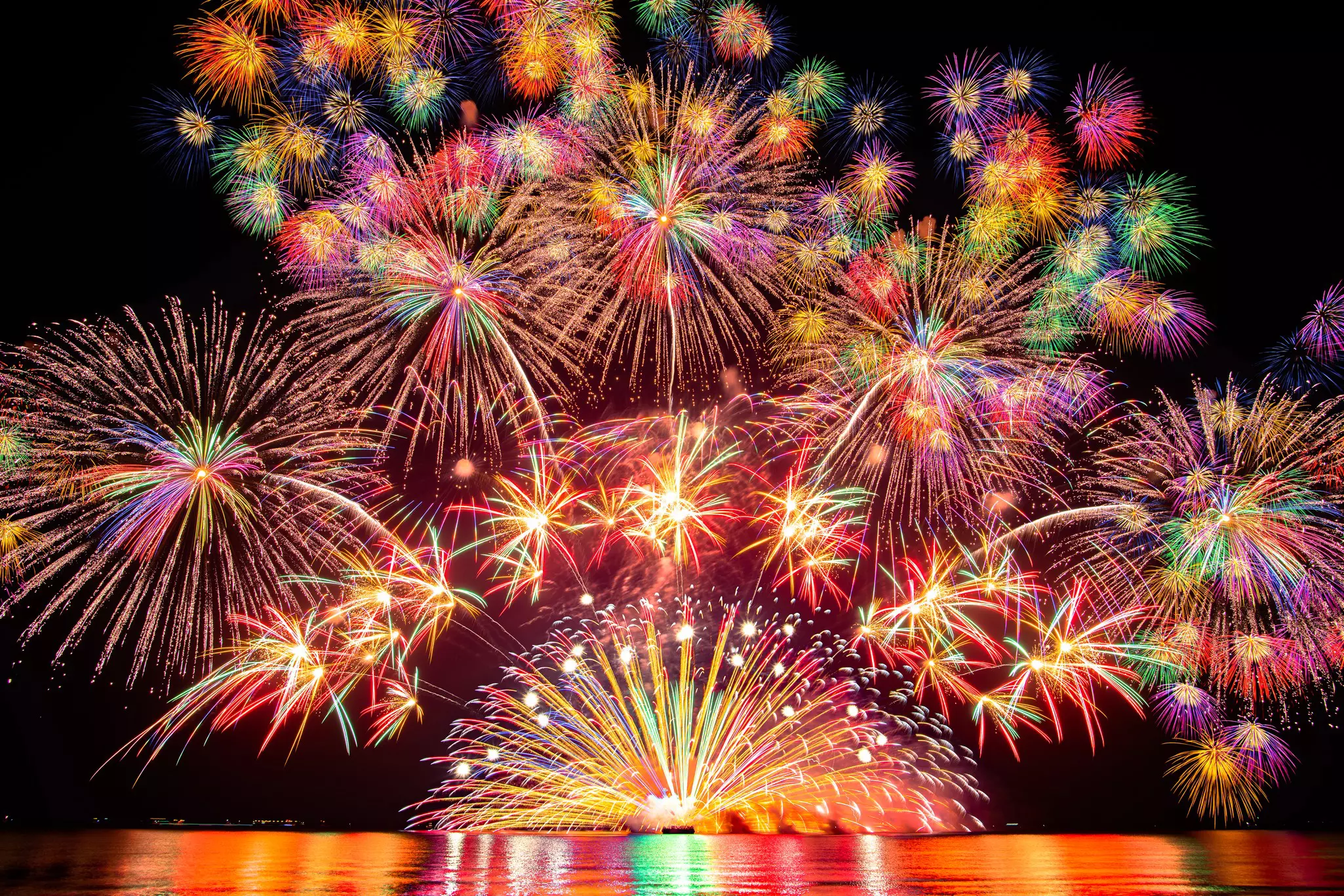 Fireworks, and a red and purple sunset compete with the glow of lights in the city of Portland and on a nearby bridge