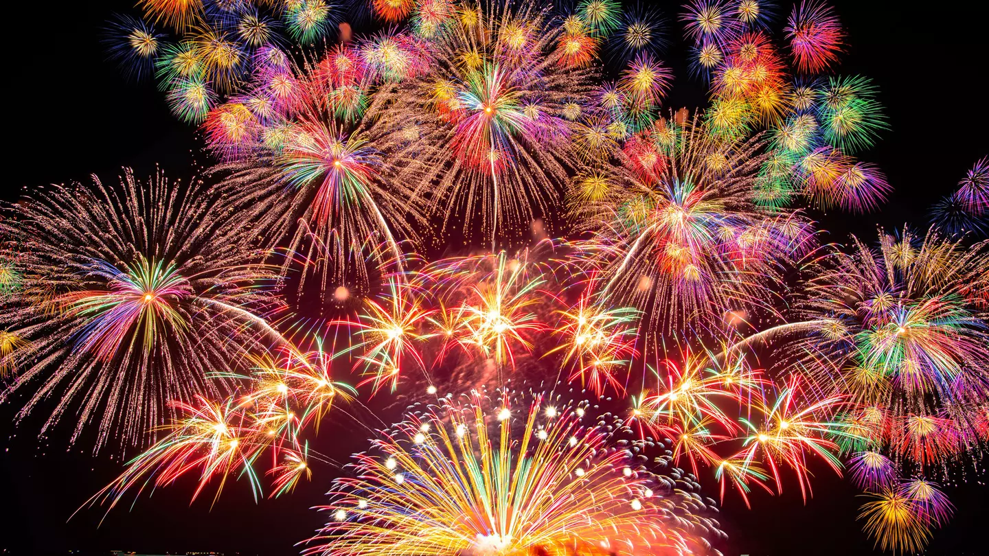 Fireworks, and a red and purple sunset compete with the glow of lights in the city of Portland and on a nearby bridge