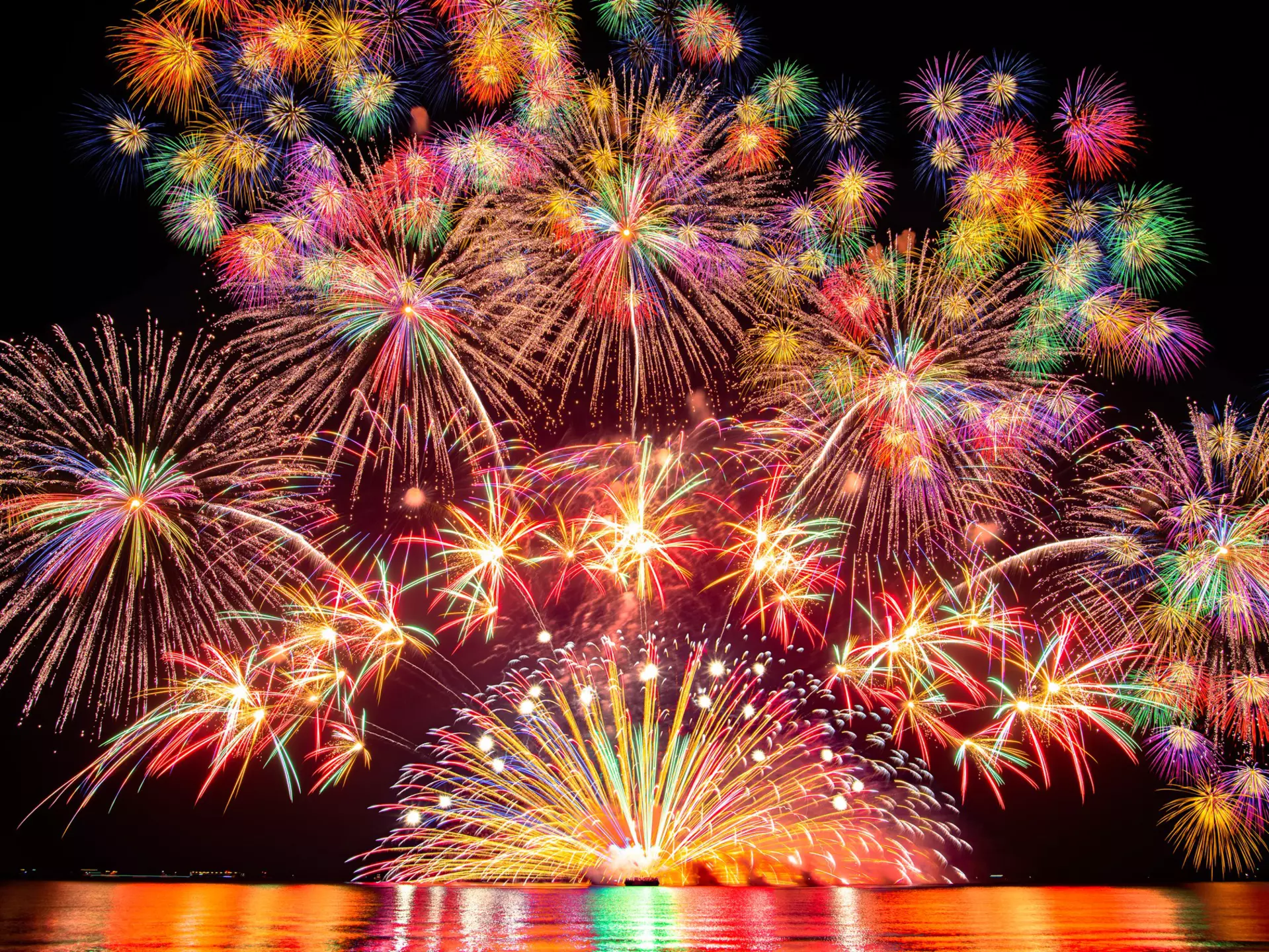 Fireworks, and a red and purple sunset compete with the glow of lights in the city of Portland and on a nearby bridge