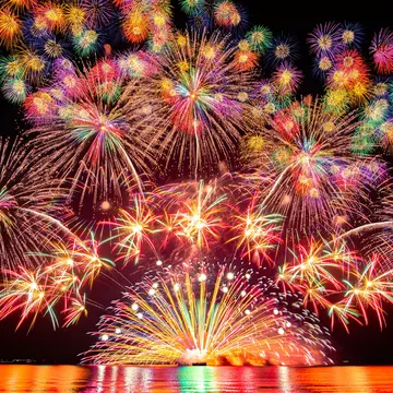 Fireworks, and a red and purple sunset compete with the glow of lights in the city of Portland and on a nearby bridge