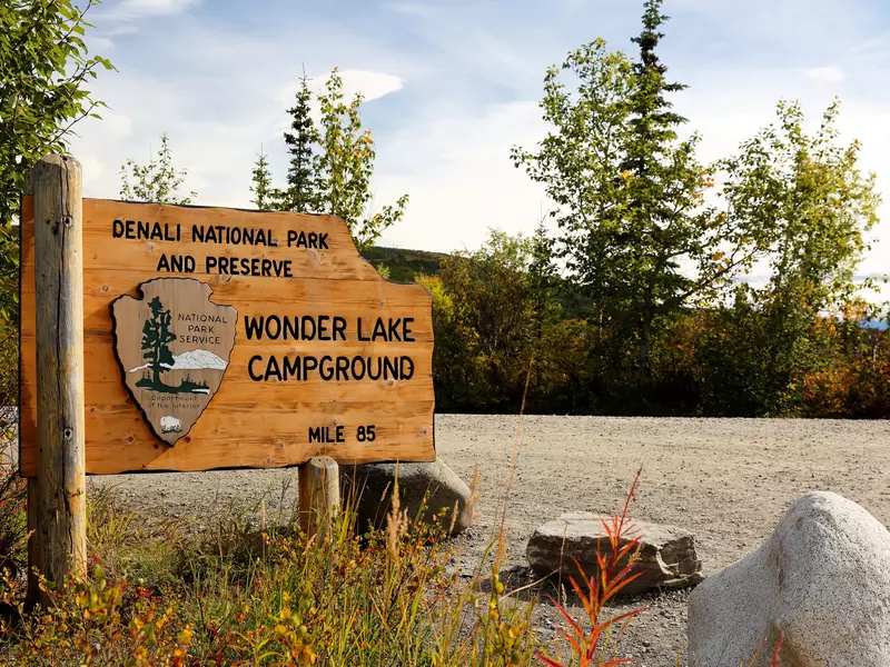 Denali National Park Wonder Lake Campground sign at Wonder Lake with tree and beautiful mountain in the background at late afternoon