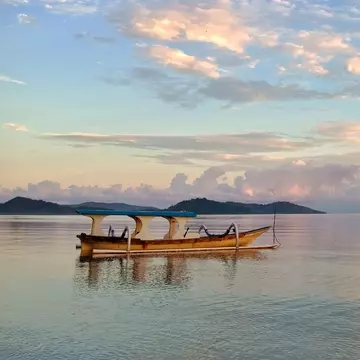 A fishing boat on calm water after sunset.