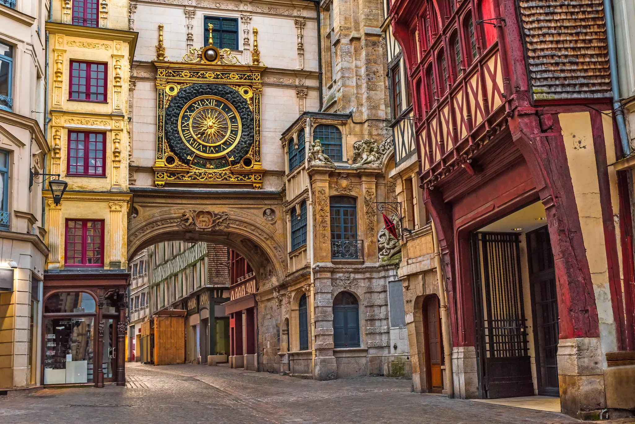 Old cozy street in Rouen with an ornate clock over a passageway.