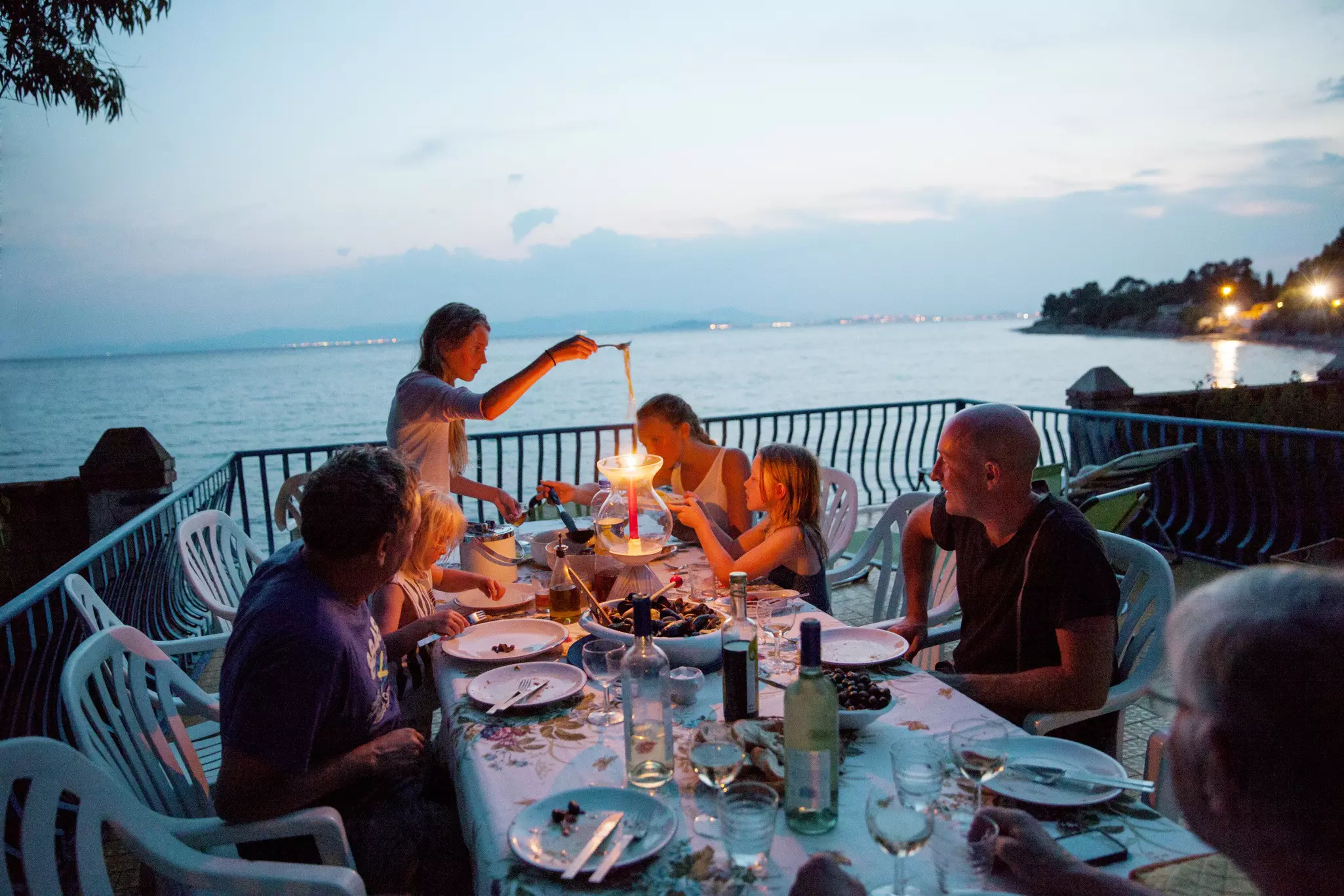 Family having meal on patio overlooking sea.