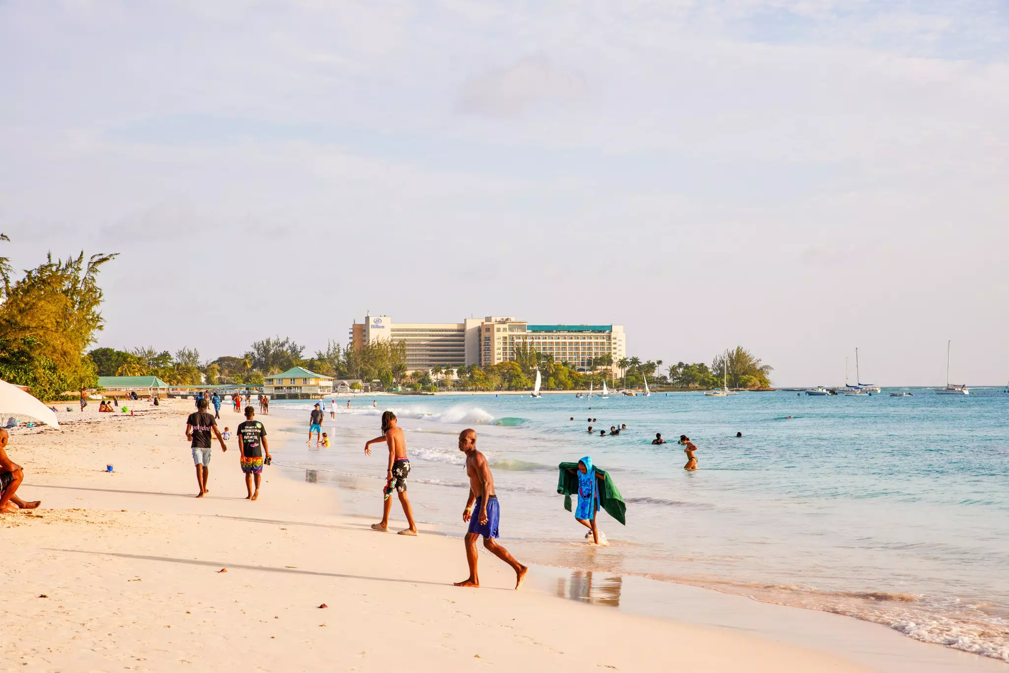 People scattered on a beach shore. Some are walking along the beach, others in the water, and some walking out of the water.