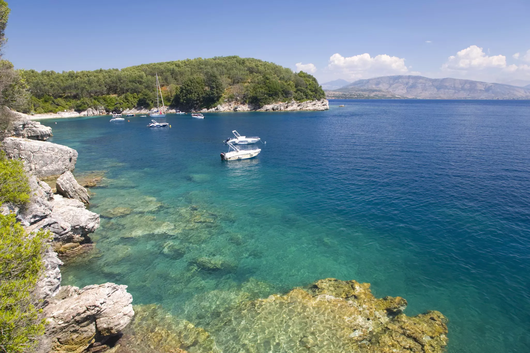 A few small boats anchored in a bay with turquoise waters, Corfu, Greece
