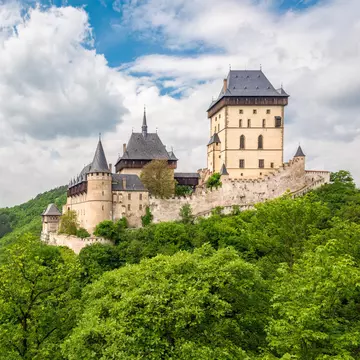 Exterior view of Karlštejn Castle, a large Gothic castle, surrounded by greenery in Czechia.