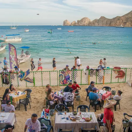 people at a table with a gate and ocean in the background 