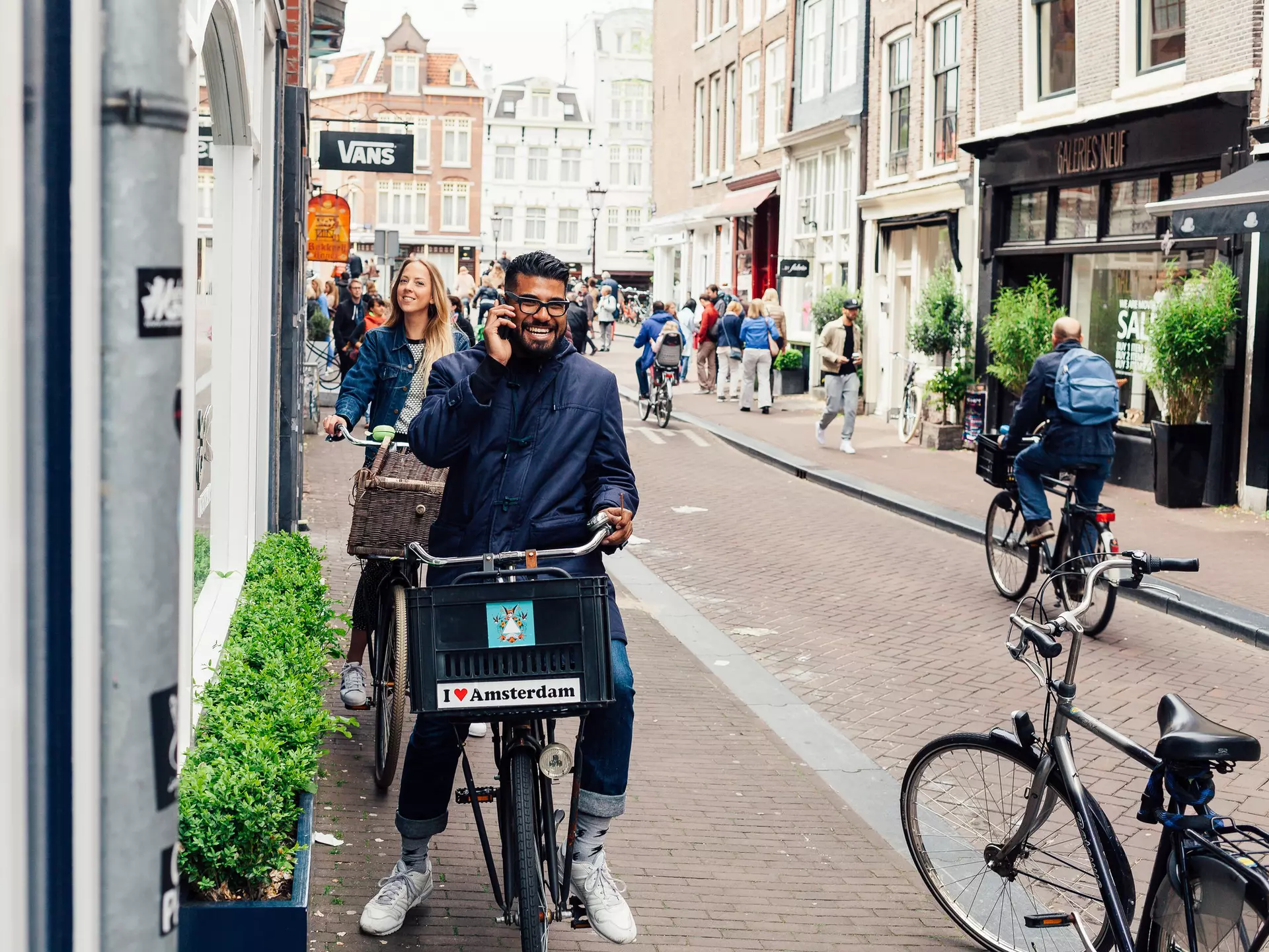 AMSTERDAM, NETHERLANDS - MAY 23, 2015: Young an happy couple on bikes on a street in Amsterdam accidentally looking into camera, happy Amsterdammers , License Type: media, Download Time: 2025-12-12T11:40:23.000Z, User: pinkjozie64, Editorial: true, purchase_order: 65020 - Marketing or Sales - this includes sponsored articles, job: Global Publishing WIP (for books) , client: Amsterdam 14, other: Jo-anne Riddell