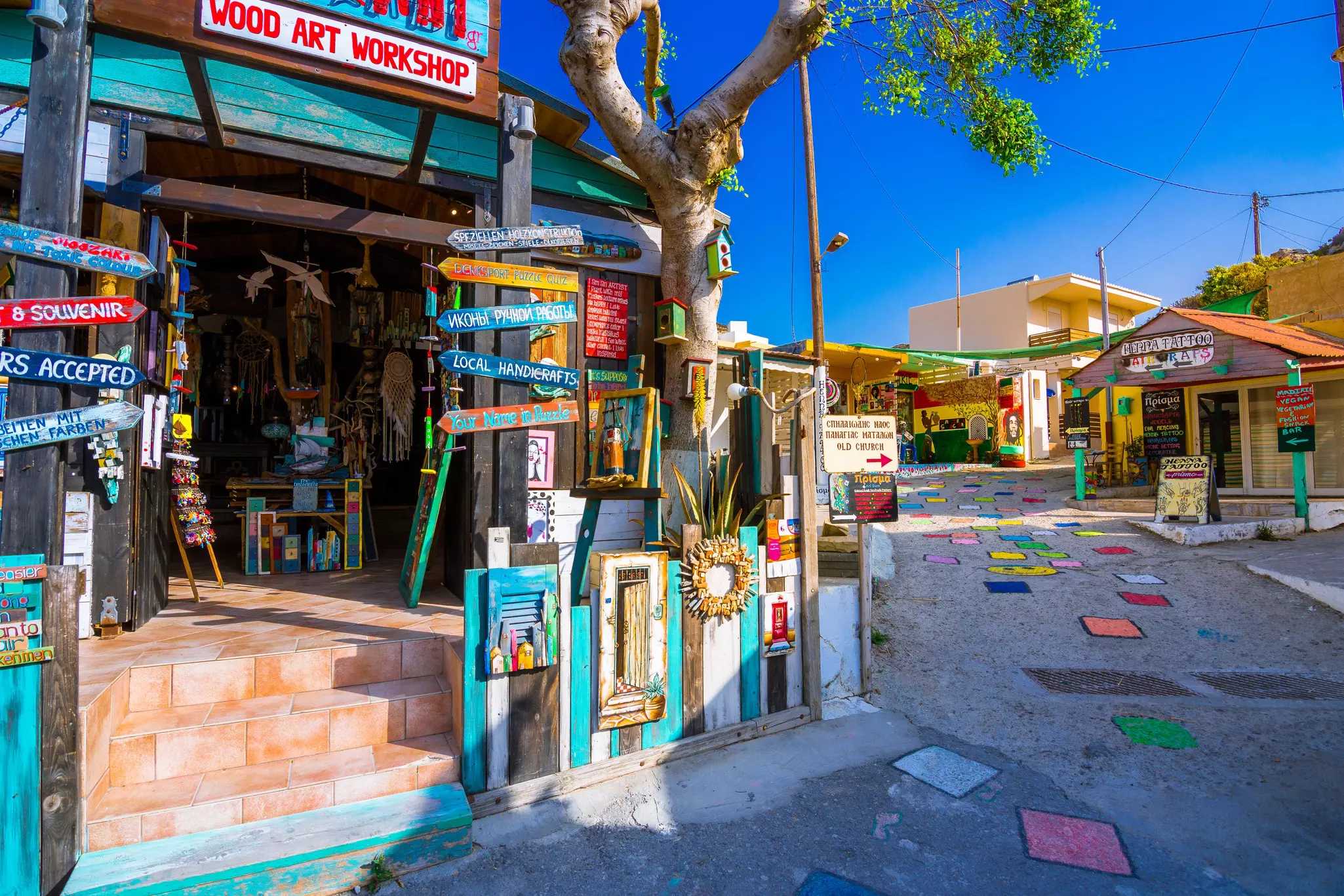 Shop with signposts on a colorful street in Matala village, Crete, Greece 