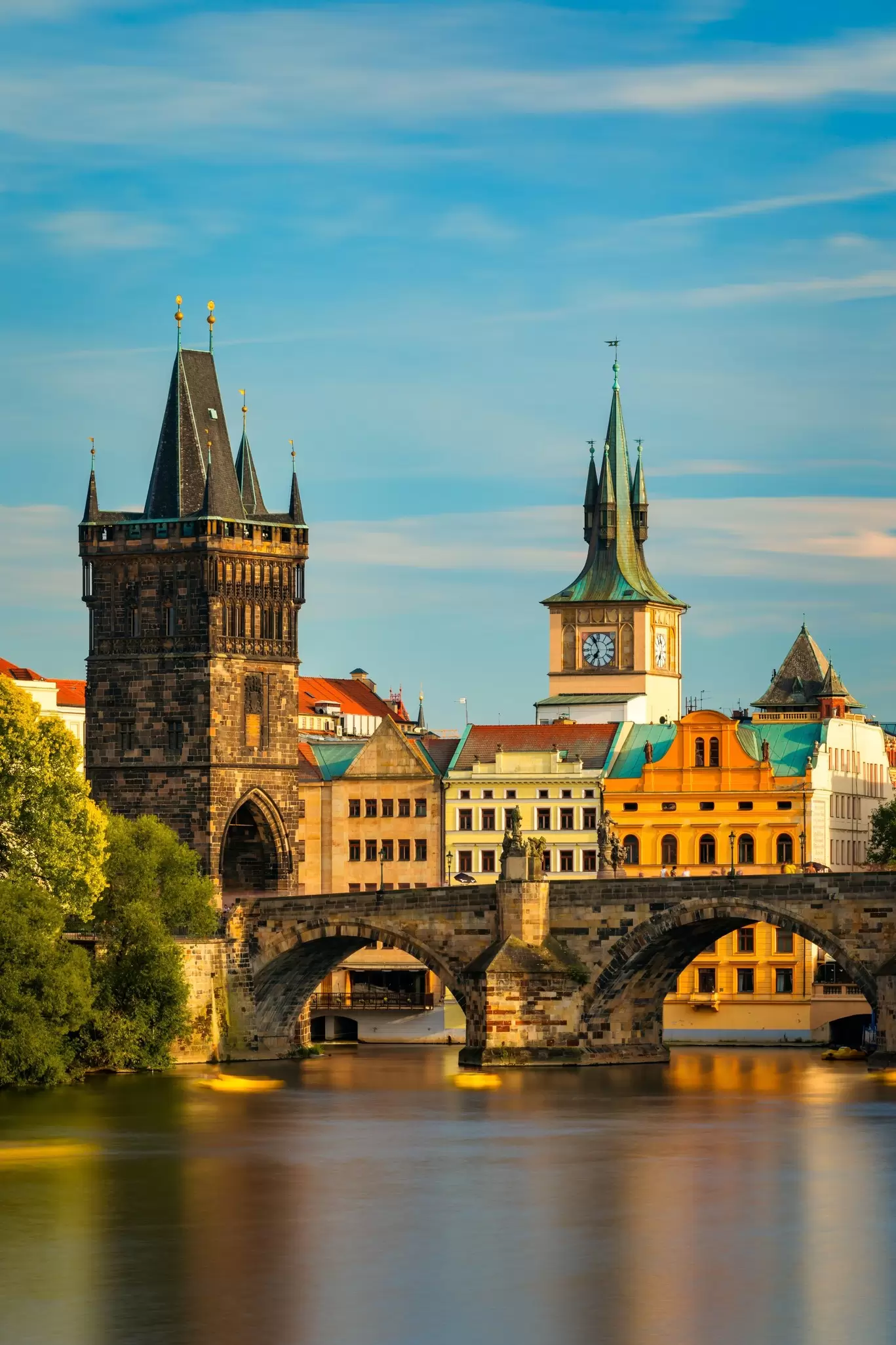 Charles Bridge and Old Town Bridge Tower over the Vltava River in Prague at golden hour.
