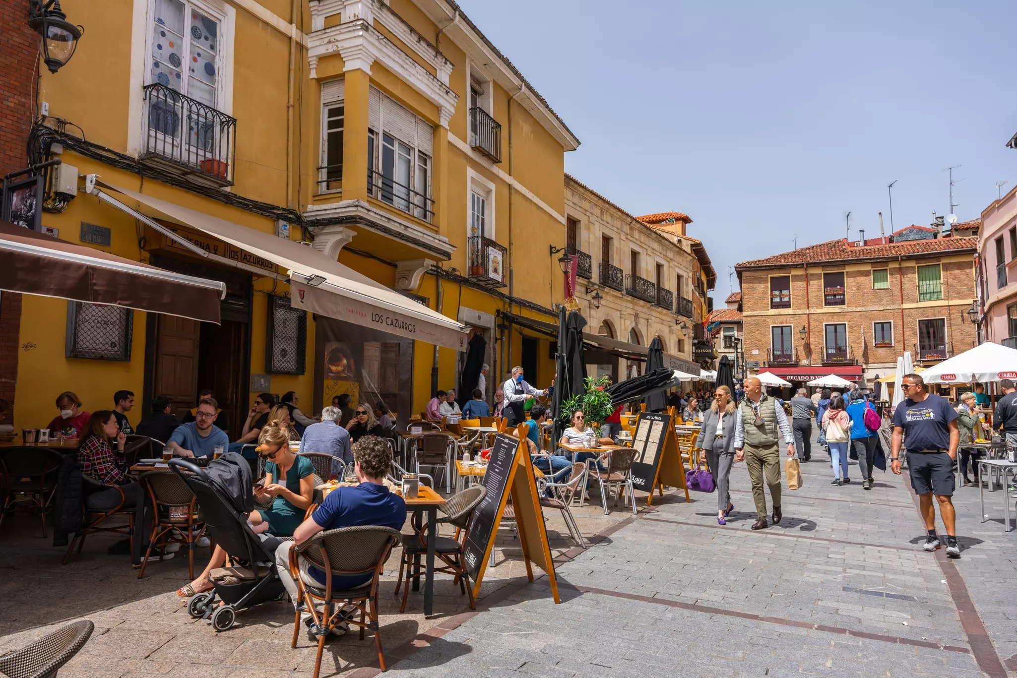 Toursits eating and drinking at cafes with outside tables in a city square