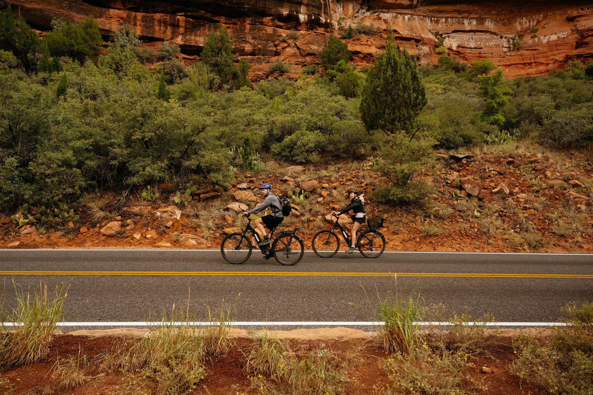 Bikers pass a rocky wall in Zion National Park, Utah, USA.