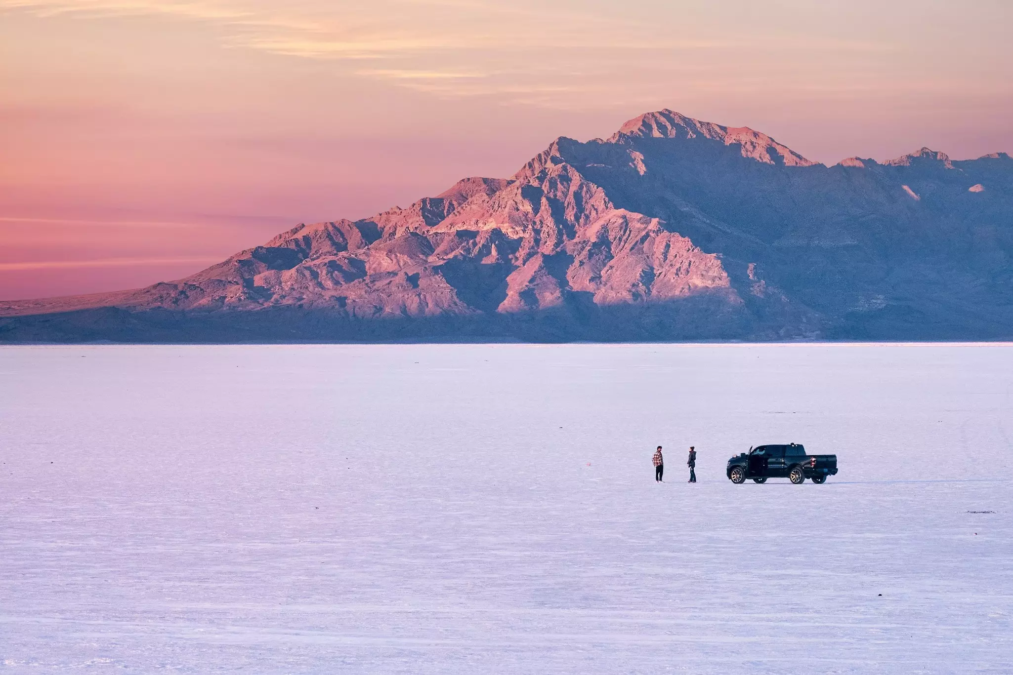 Two people with car on Bonneville Salt Flats near Salt Lake City at sunset. Utah. USA