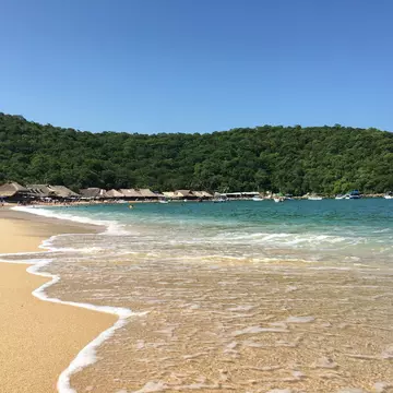 Playa El Maguey. Santa Maria Huatulco, Oaxaca, Mexico with wooden beach huts and swimmers
