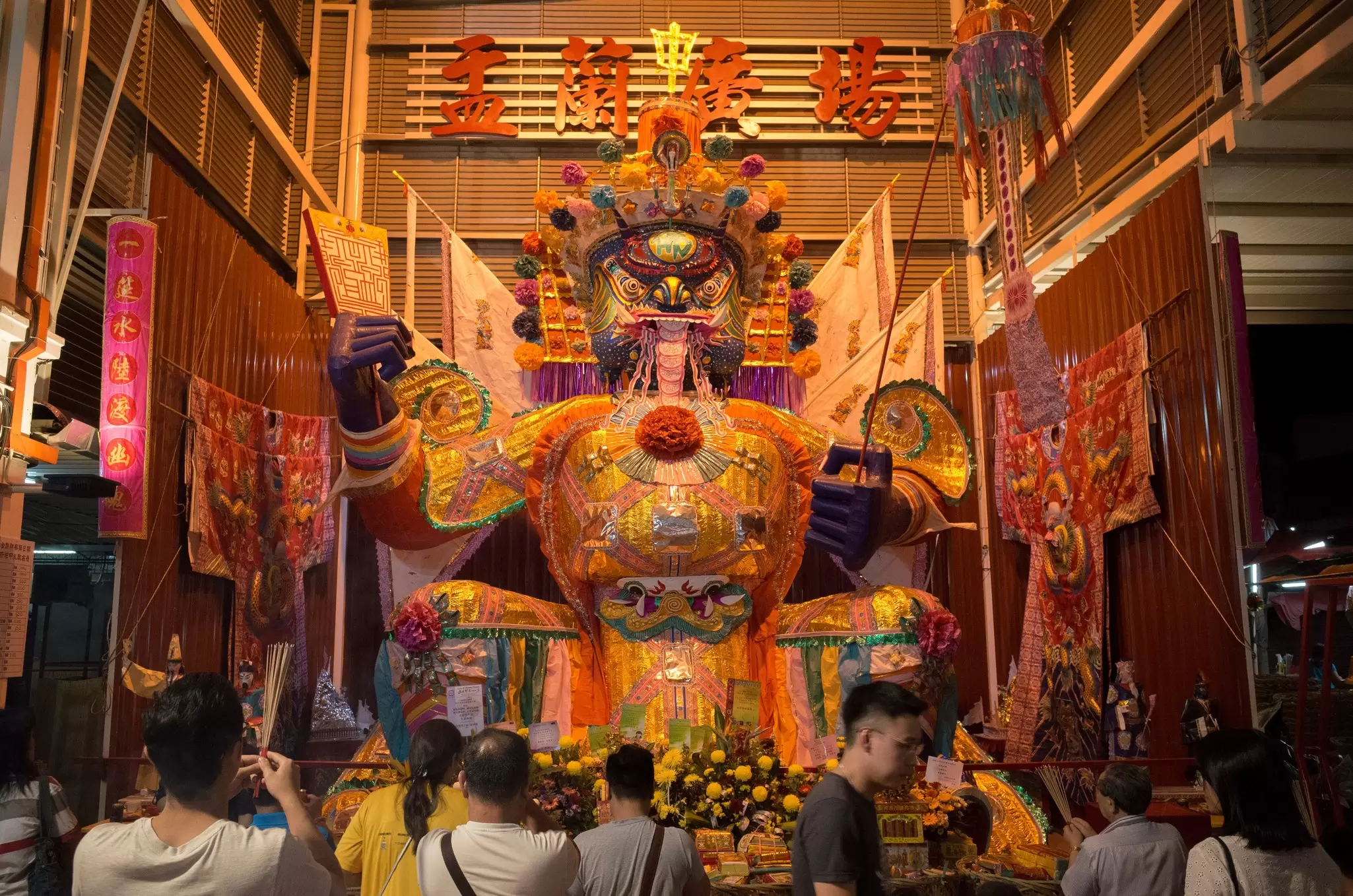 People stand in front of an effigy of a god in a temple in Penang, Malaysia