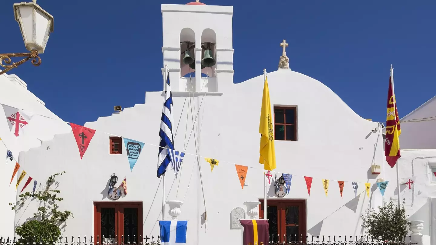 A whitewashed church with colorful triangular flags hanging across the front.