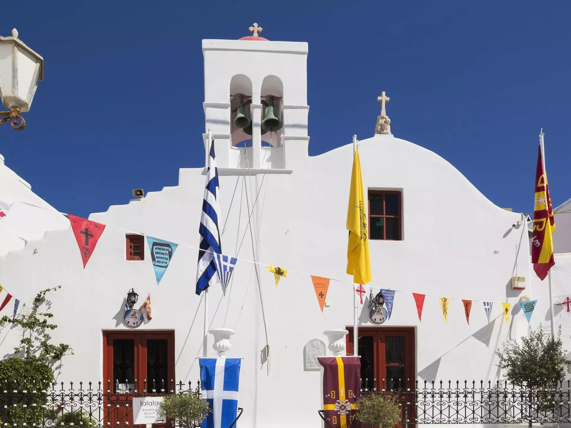 A whitewashed church with colorful triangular flags hanging across the front.