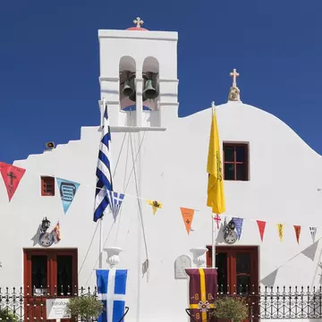 A whitewashed church with colorful triangular flags hanging across the front.