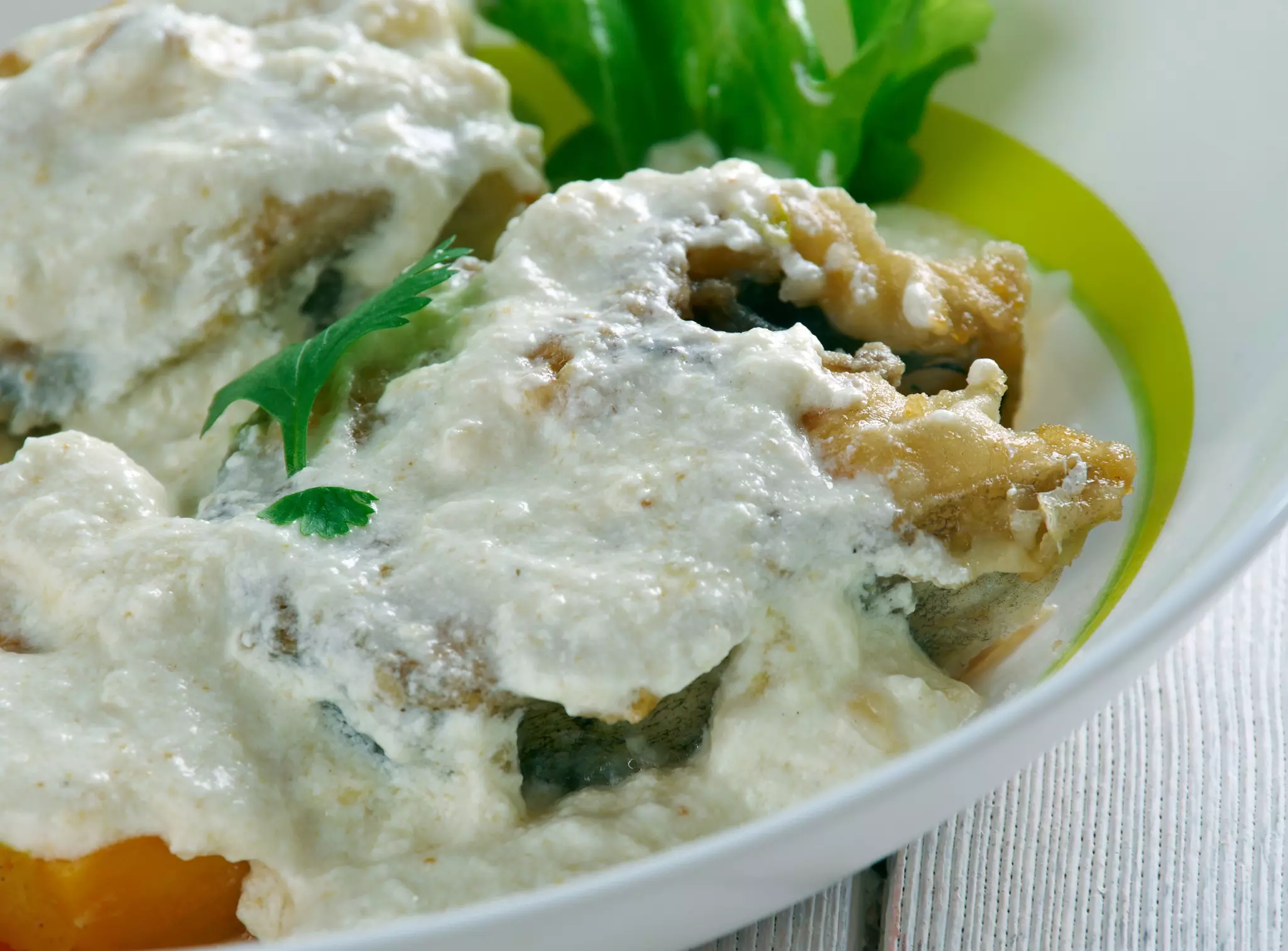 A fish dish covered in a thick white coconut sauce.