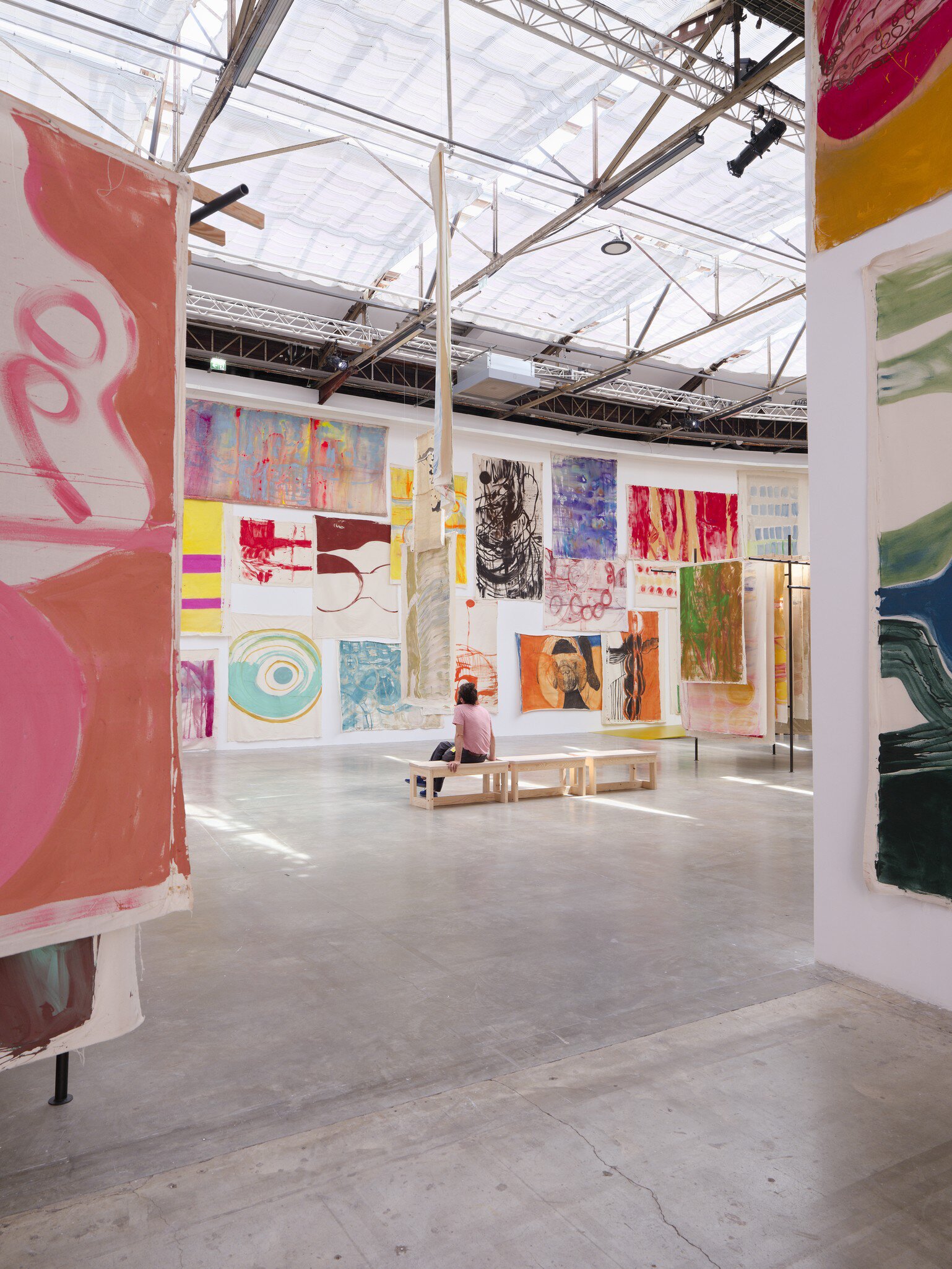 A woman sits on a bench and admires the surrounding artwork in Palais de Tokyo, Paris.