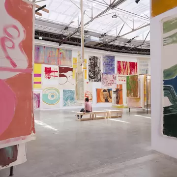 A woman sits on a bench and admires the surrounding artwork in Palais de Tokyo, Paris.