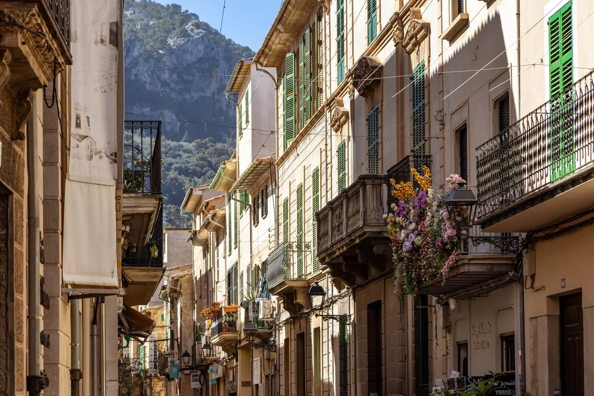 Balconies on a historic street, some with flowers.