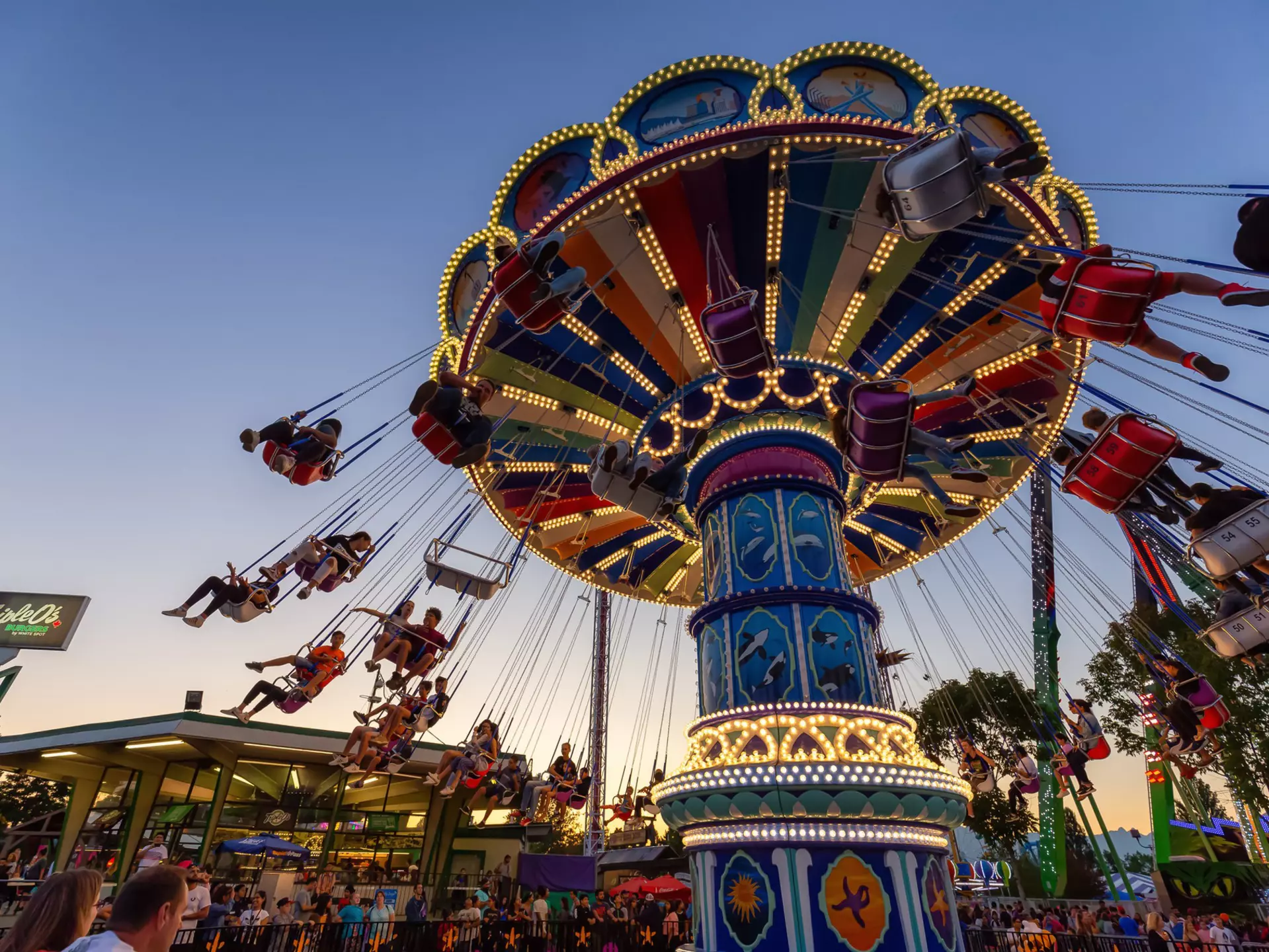 A swing carousel in motion, with children riding in the swing seats