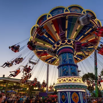 A swing carousel in motion, with children riding in the swing seats