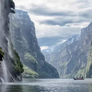 We see a tourist boat on the horizon in the middle of the canyon on the left we see the​ Christmas Tree Waterfall or Cascada Arbol de Navidad, ​in the background, in the right the rest of the canyon. ..This is a beautiful view of the Sumidero Cany...