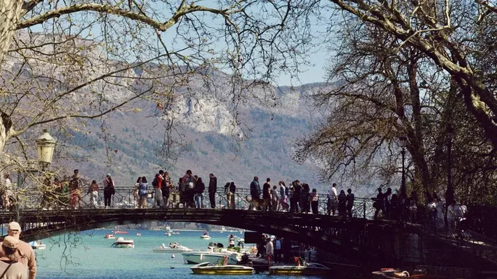 People sit on the edge of a canal on a sunny day