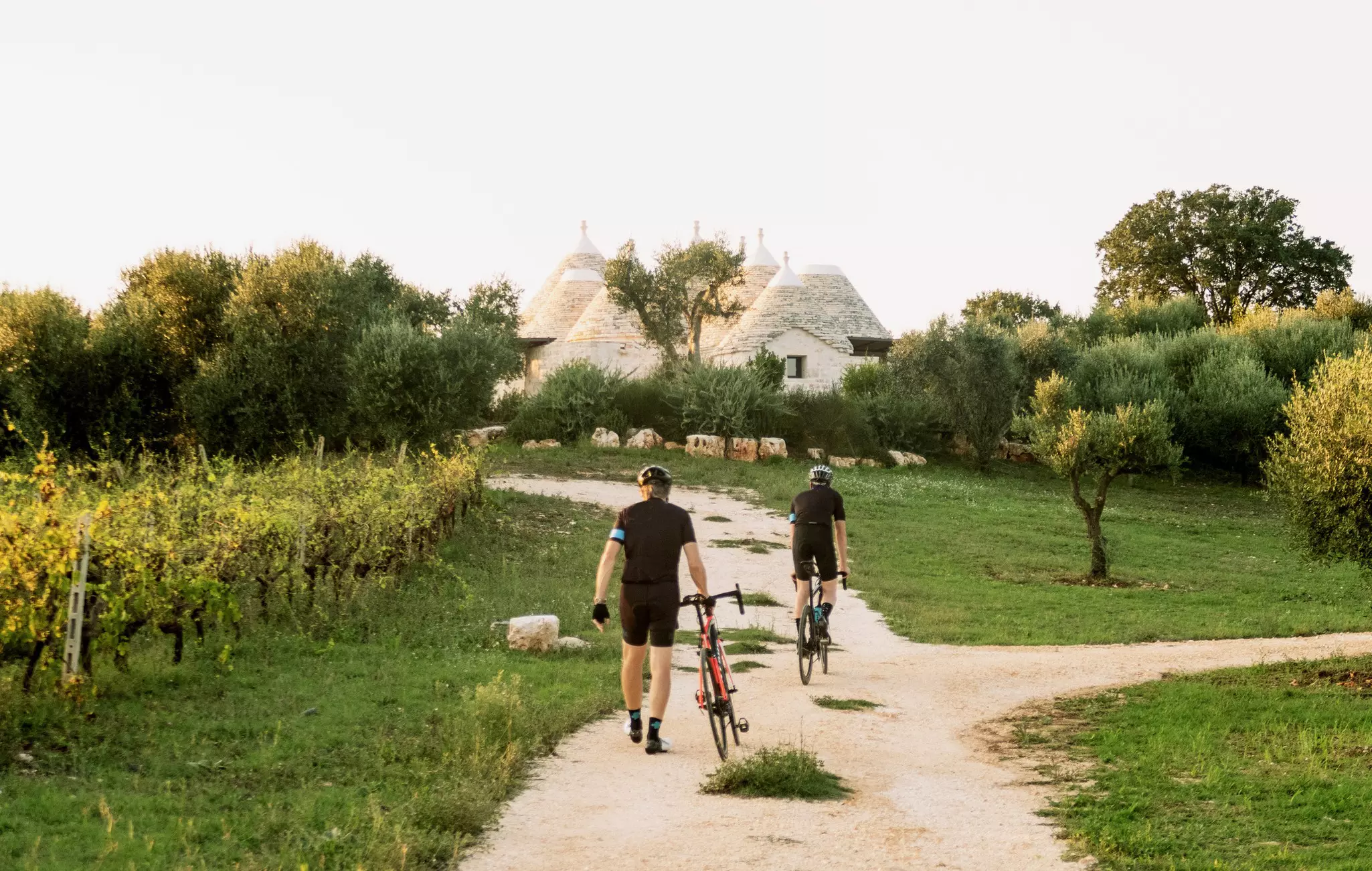 Two cyclists head toward conical white limestone buildings