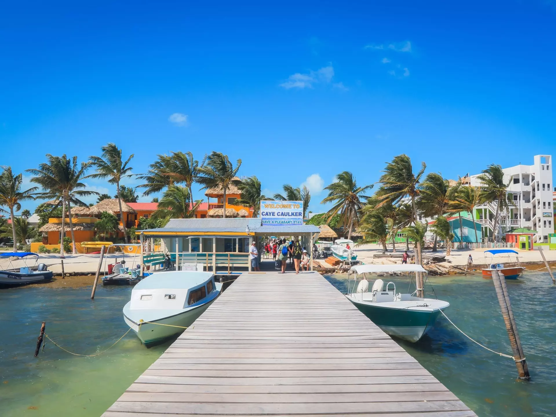 Boats line a colorful beachside pier in Belize on a sunny day. 