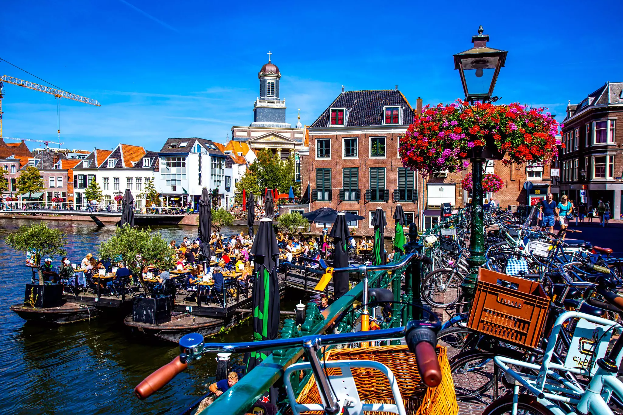 People on a floating barge with drinks in a canal in central Leiden, South Holland, Netherlands