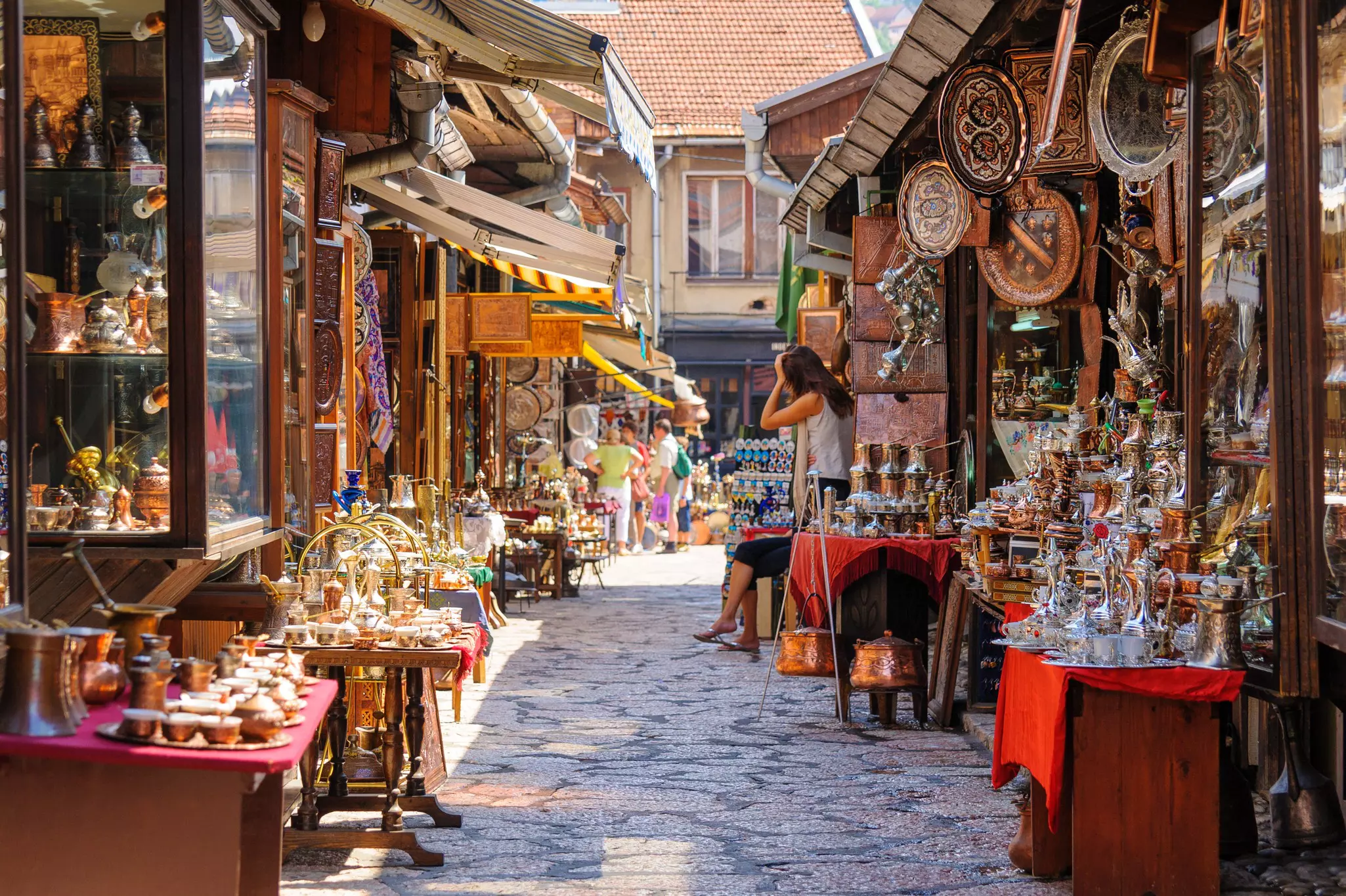 A cobbled street lined with market stalls selling dishes, glasses and other kitchenware.