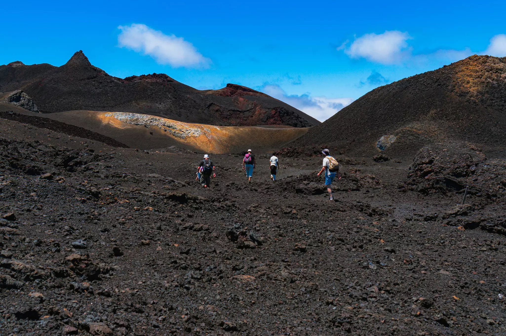 Hikers cross a volcanic landscape on Isabela in the Galápagos Islands. 