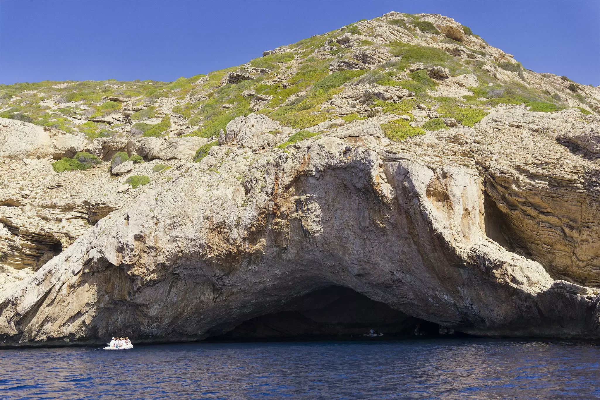 A small boat explores the picturesque coast of Cabrera Island