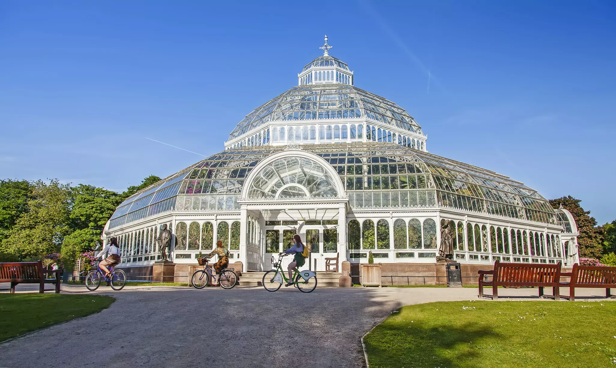The Palm House in Sefton Park, with cyclists and benches nearby.
