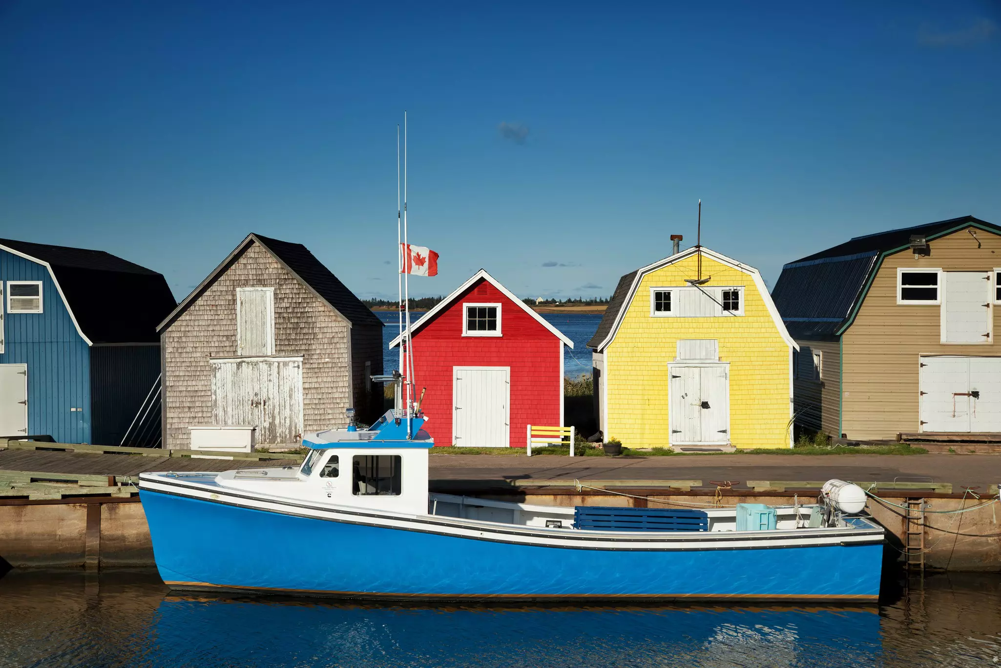 Blue fishing boat in front of oyster barns in New London, Prince Edward Island.