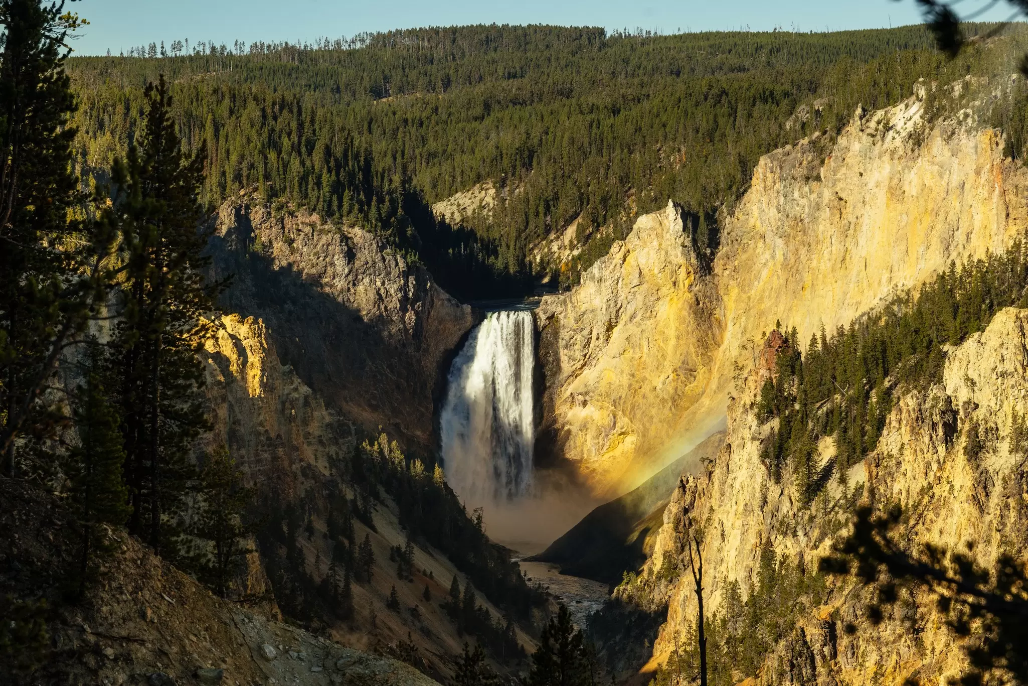 Towering waterfall tumbling into a valley surrounded by sheer cliff faces and forests