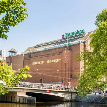Exterior view of the building housing the Heineken Experience on a sunny day in Amsterdam.