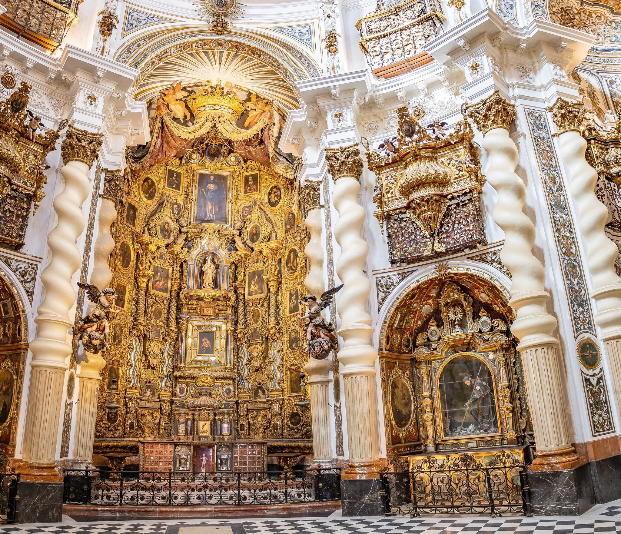 The interior of a church reveals a lavish gilded altarpiece surrounded by spiral-patterned columns.