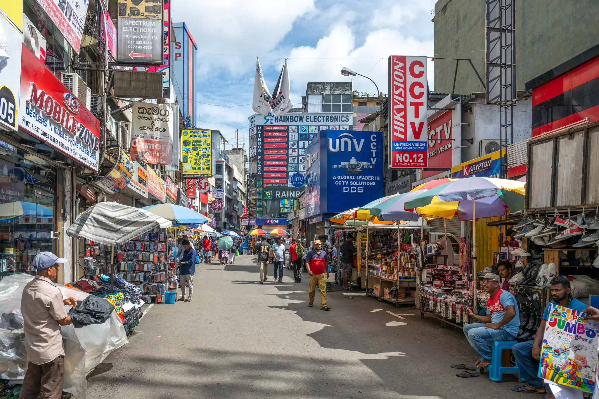 A busy street lined with eletronics stores and market stalls.