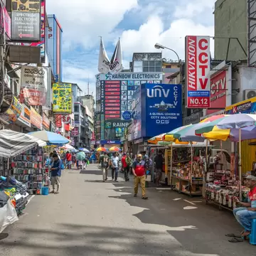 Crowded street market with colorful signs, vendors, and shoppers in Pettah district of Colombo, Sri Lanka