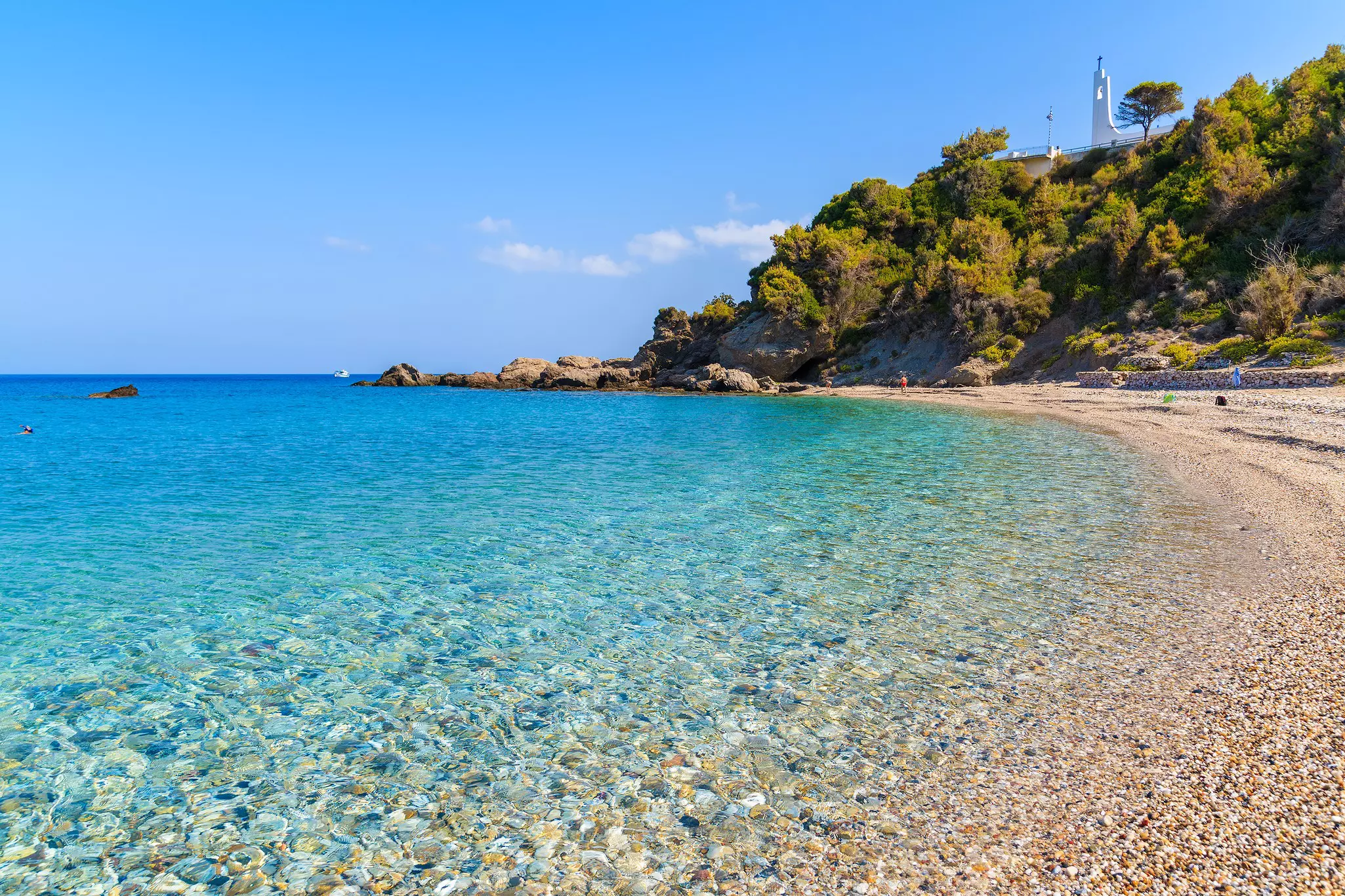 A beach with pebbles and turquoise crystal clear water.