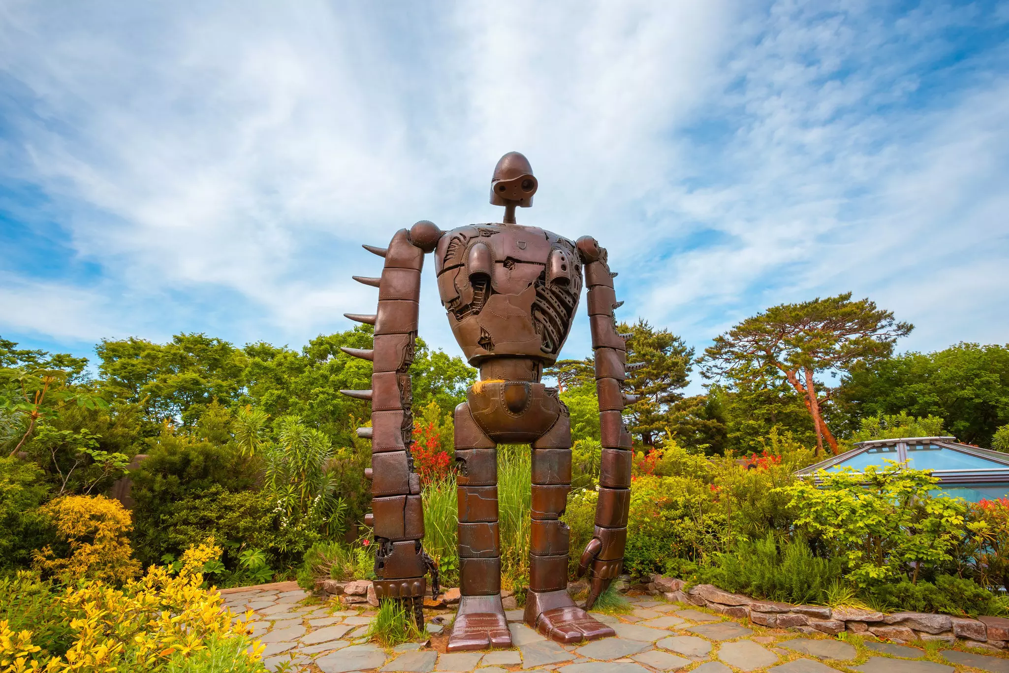 A metal robot statue in a flowering garden at a museum in Tokyo.