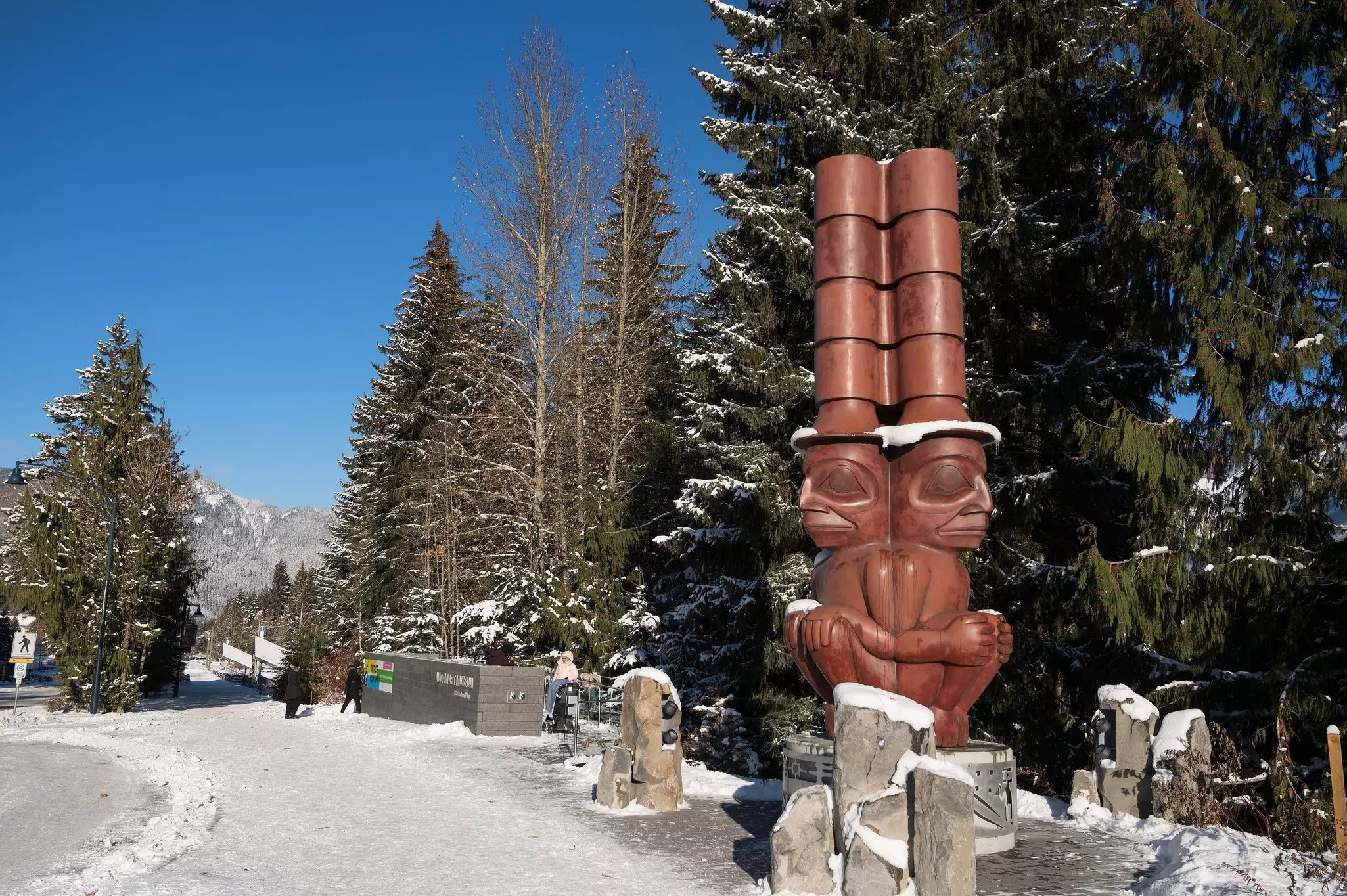 A wooden statue outside the Audain Art Museum with snow on the ground
