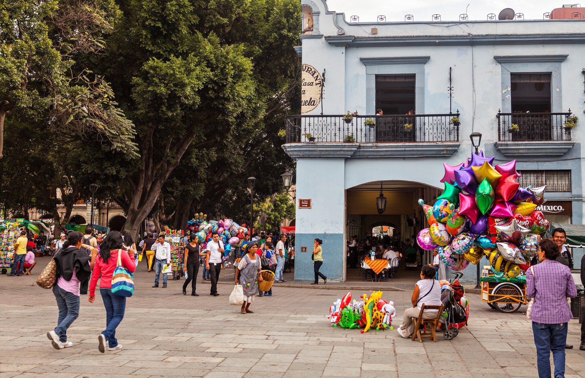 Oaxaca, Mexico - May 7, 2014: Some locals in the Zocalo (Town Square). A street vendor selling colorful balloons.